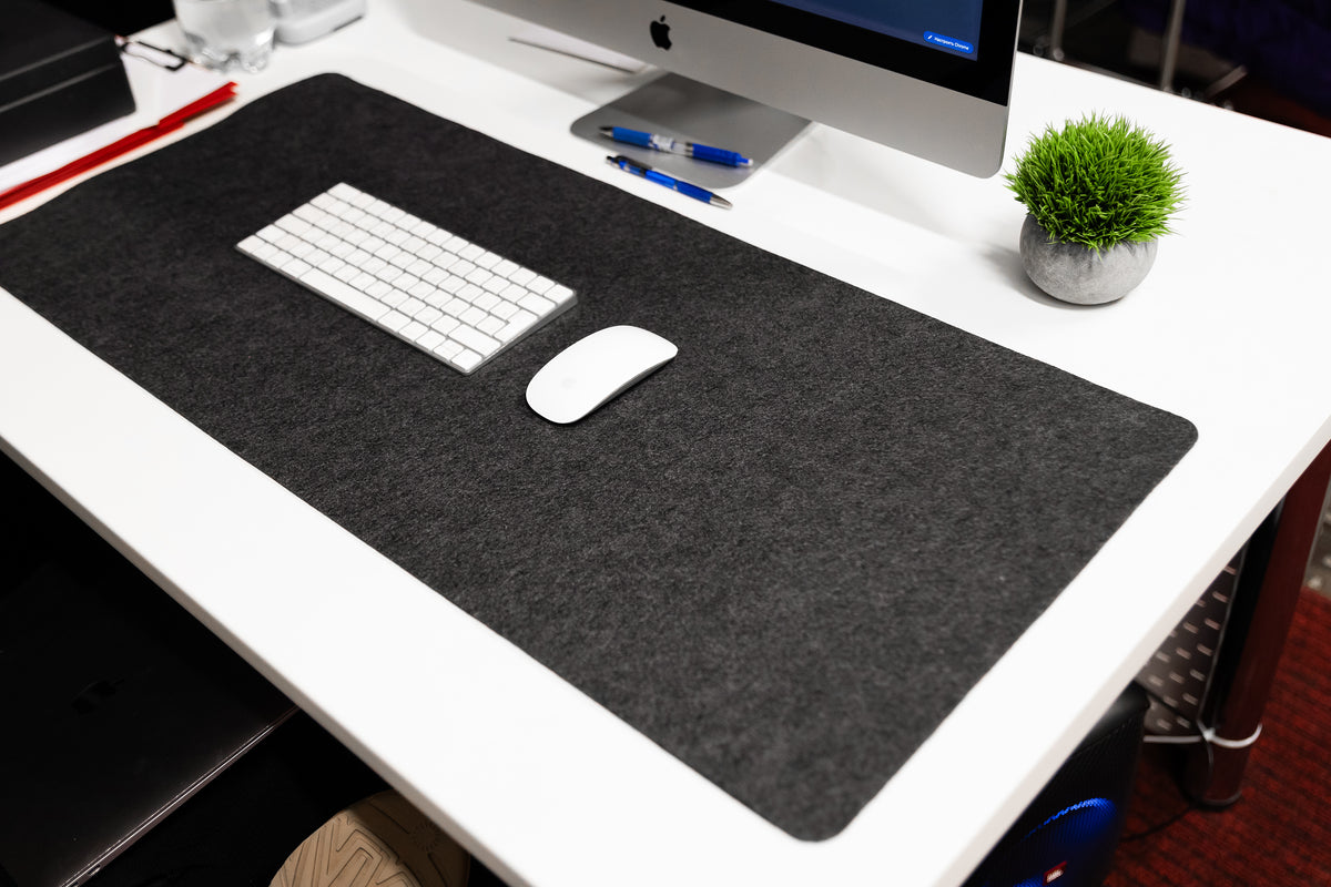 Gray desk mat on a white desk with a computer setup