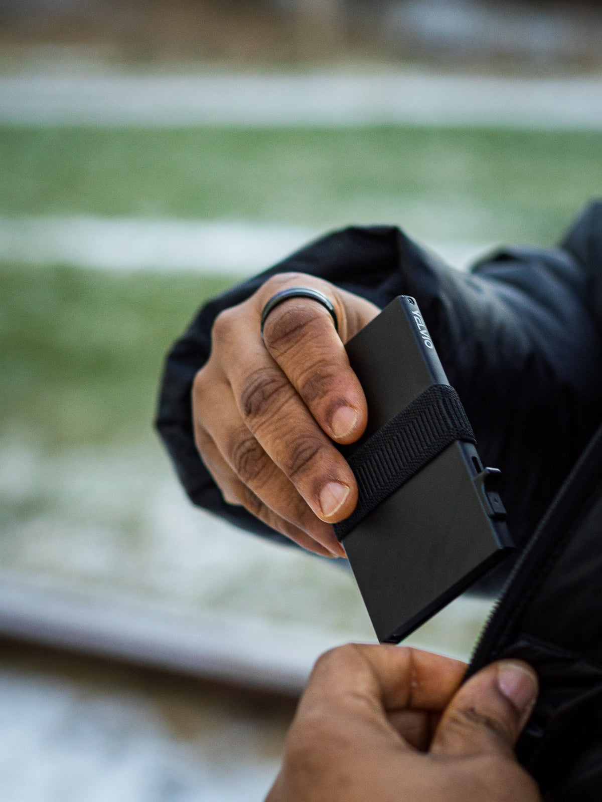 Person holding a black wallet with a blurred outdoor background